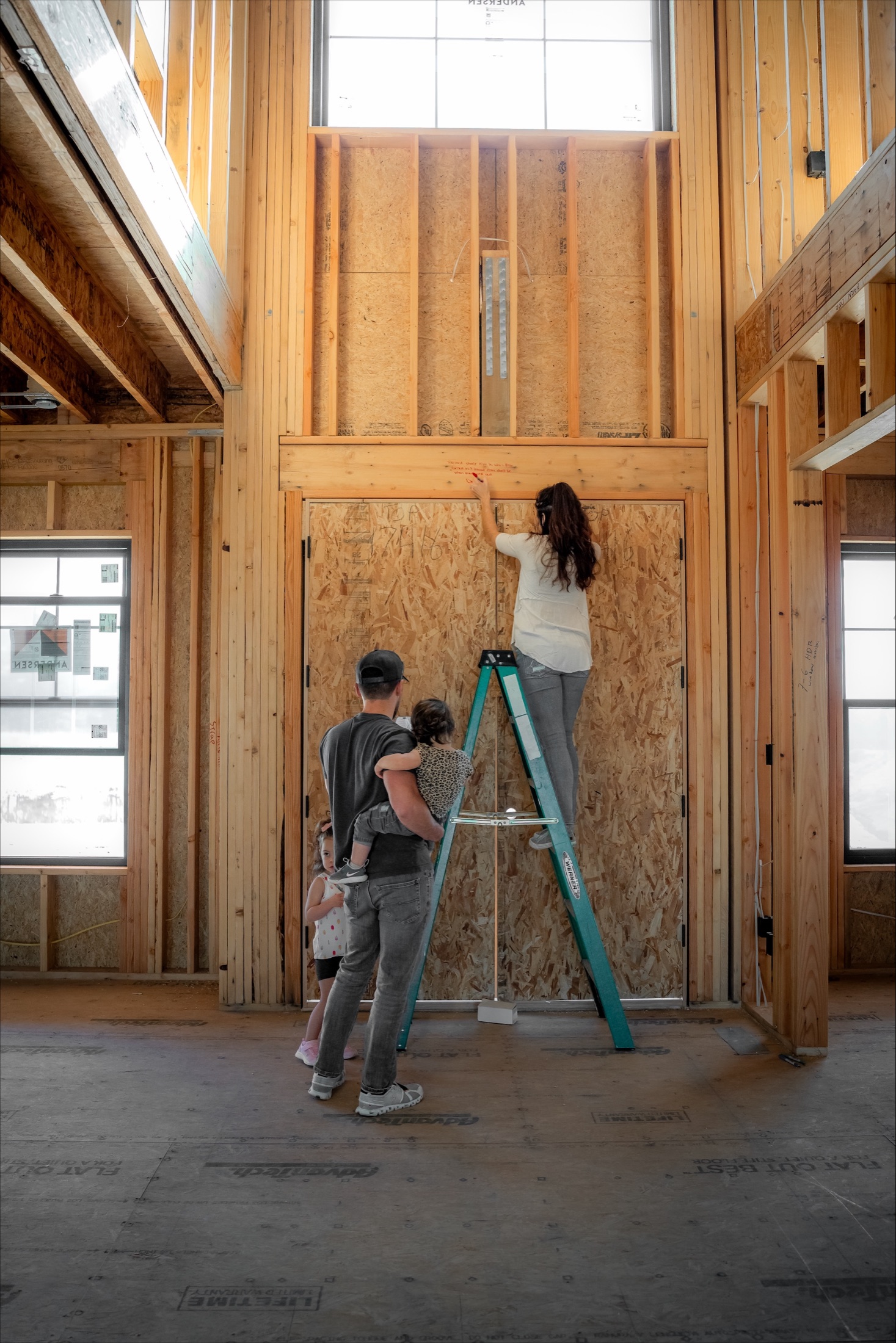 A family writing blessings on the framing of their home